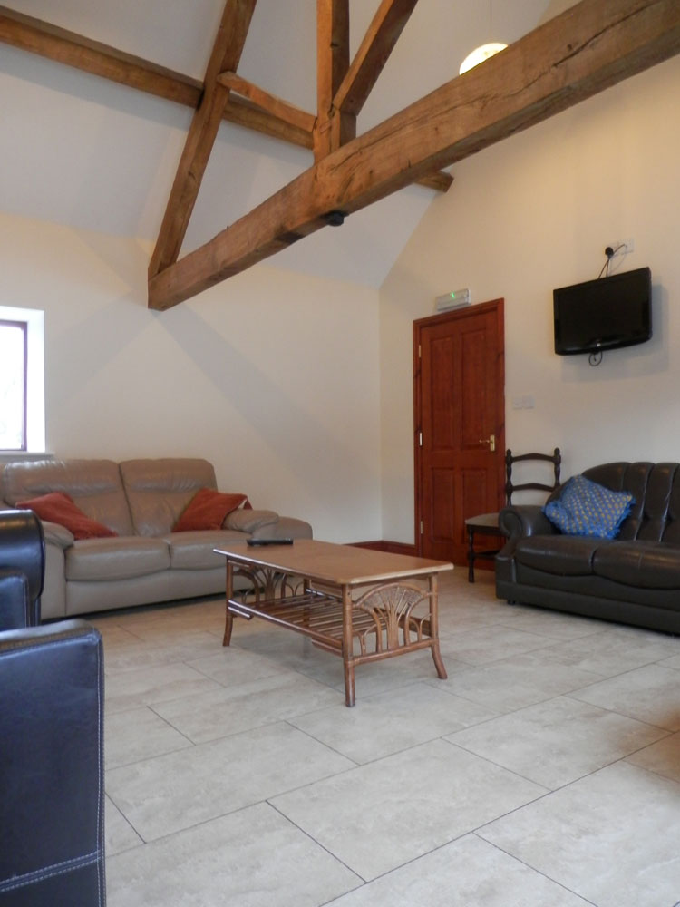 Two sofas in a spacious room with wooden beams at Haye Farm sleeping barn
